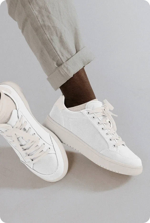 Minimalist white leather sneakers with textured panel and beige platform sole on model with cuffed linen pants