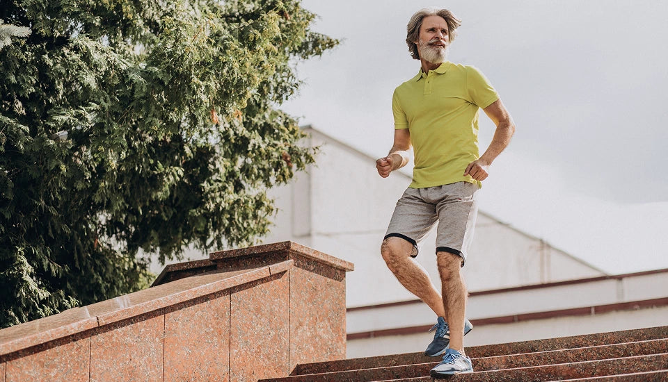 Man in a green shirt and gray shorts running on steps outdoors